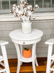 White side Table between rocking chairs with a farmhouse vase and cotton stems