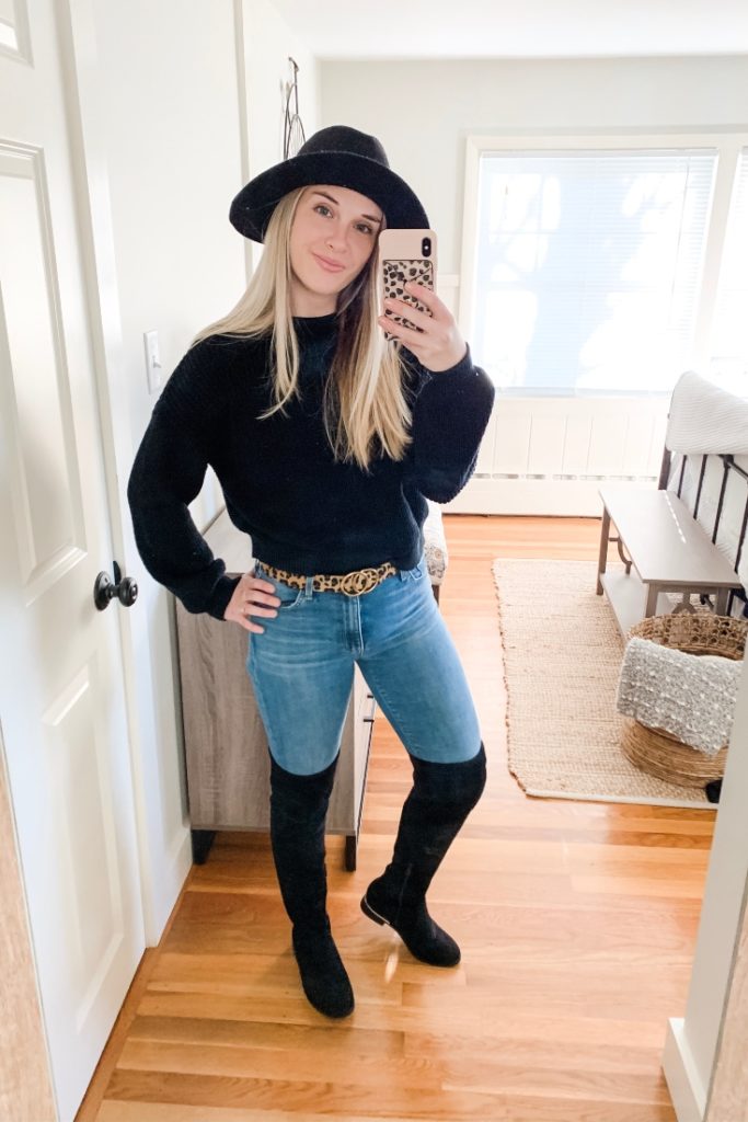 girl with a black sweater, leopard belt, jeans and black over the knee boots