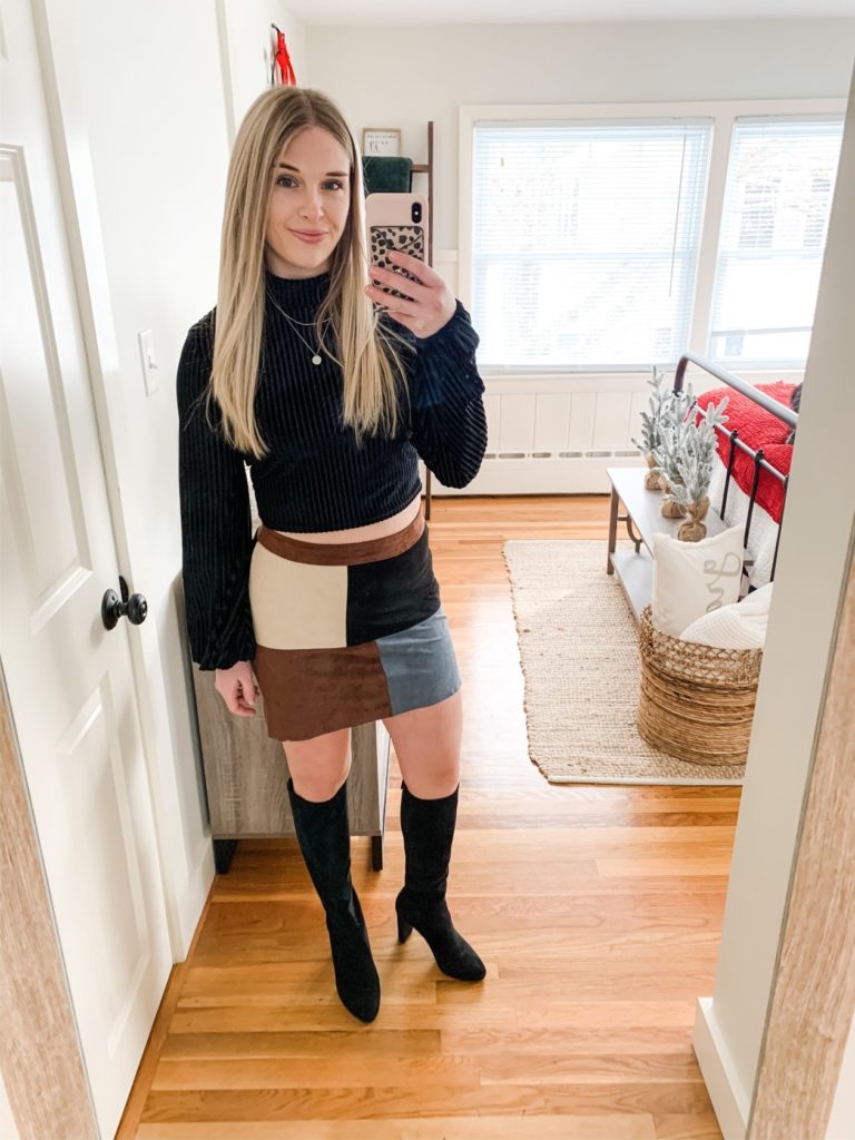 girl in black crop top, color block skirt and knee high boots