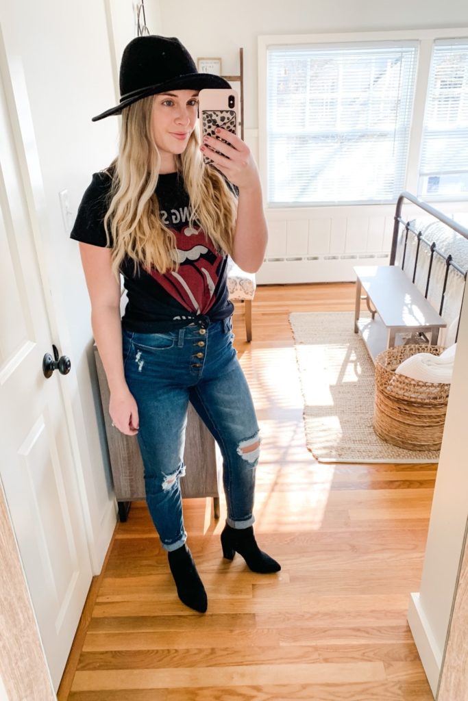 Girl in a rolling stones shirt. a black hat, distressed jeans and Black booties