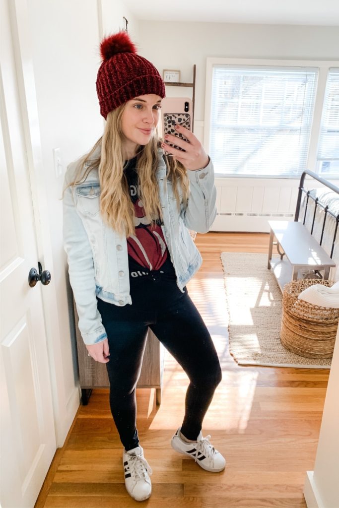 Girl in a jean jacket, rolling stones shirt. a pom pom beanie and adidas