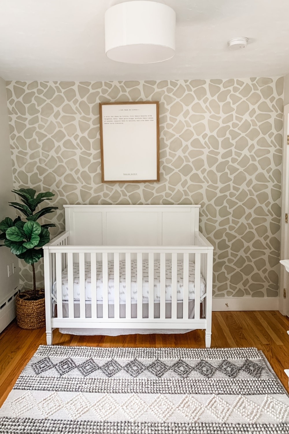 Giraffe Print nursery accent wall with crib, fiddle leaf tree and nursery wall print